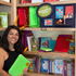 Woman holding a green book in front of a bookshelf filled with educational books and materials.